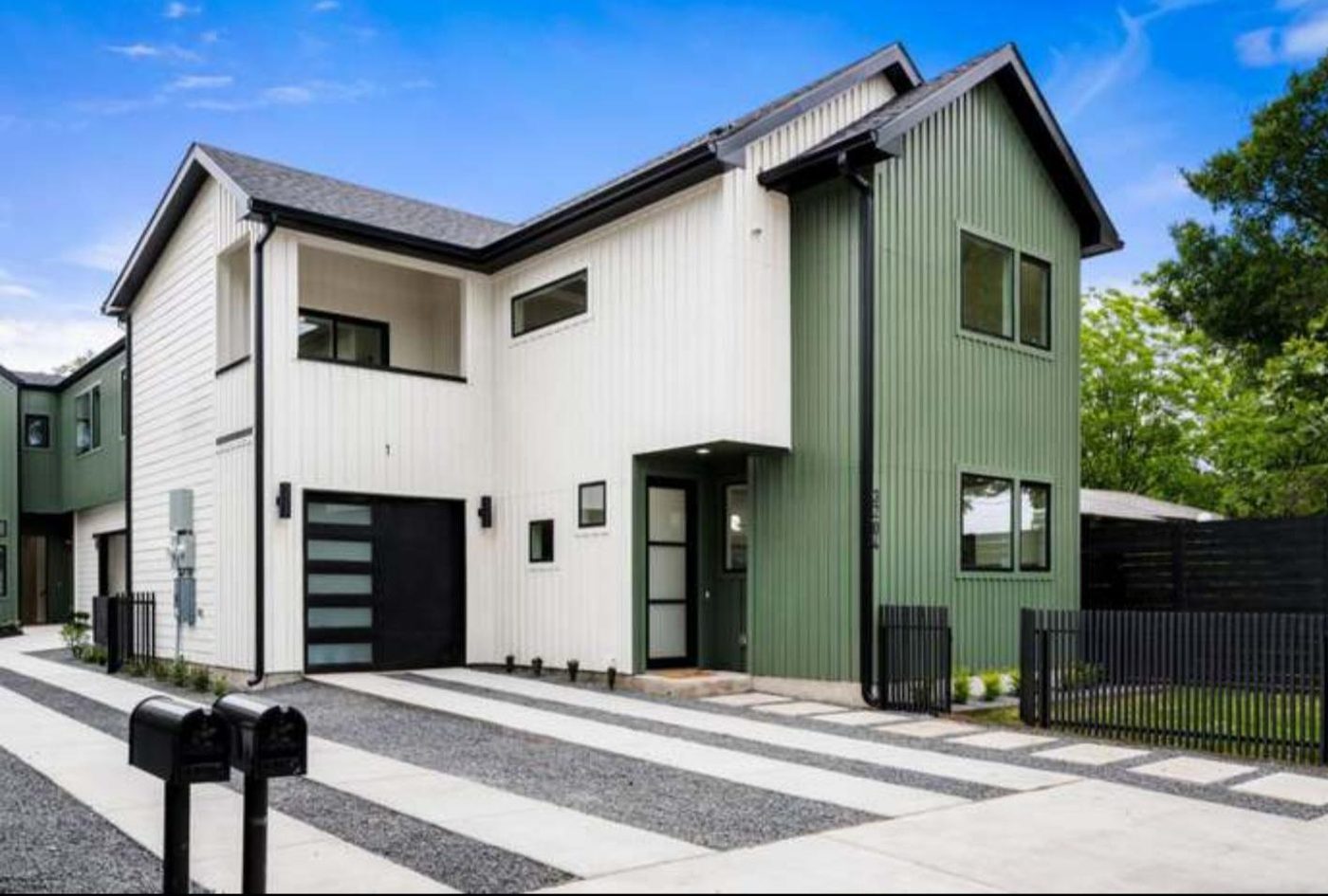 Modern green and white two-story home with vertical siding and ribbon drive